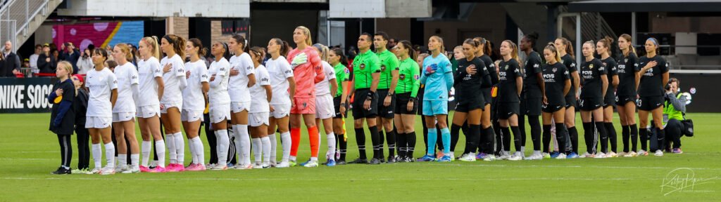 The starting 11 players for both teams stand at midfield during the National Anthem.